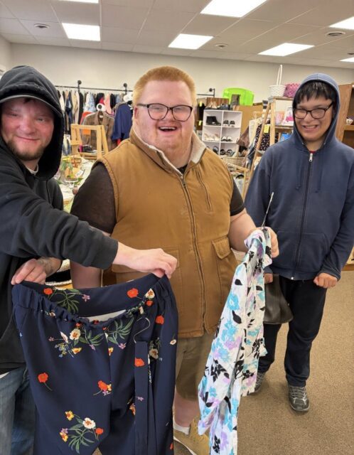 Three young men in a store two of whom are holding shirts on hangers