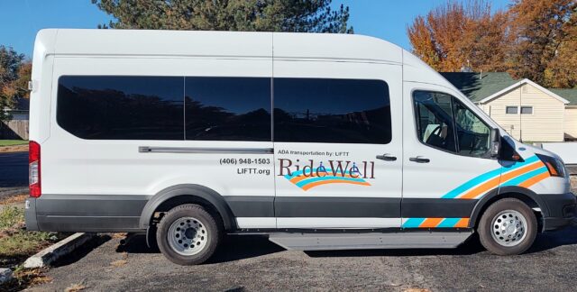 A white wheelchair accessible nine passenger van wrapped in the logo and coloring of LIFTT's ADA Rural Transportation Program Ridewell