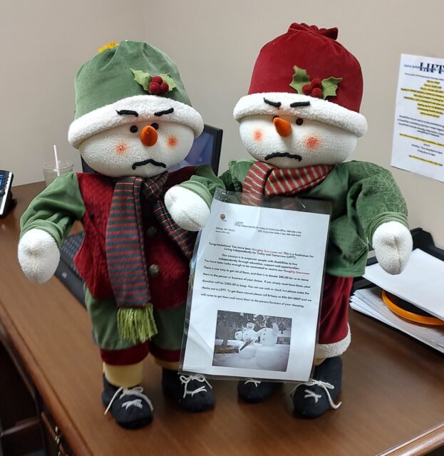 Two plush snowmen holding a flyer 
