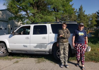 Two young white males standing beside the drivers side doors of a Chevy