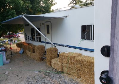 A white mobile home with a blue stripe and an awning