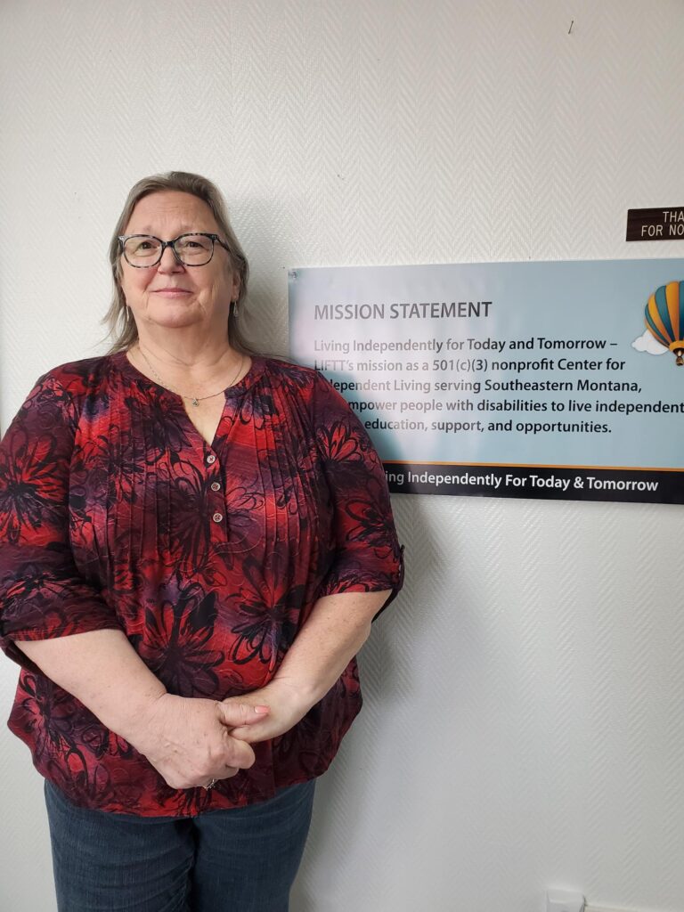 Teresa Elliot, A PCA program facilitator in LIFTT's Glendive office. A white woman with dark hair wearing glasses and a black & red shirt