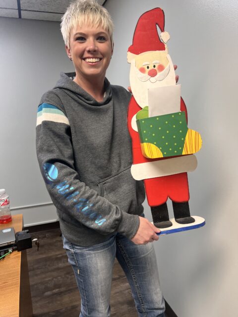short haired blond woman holding a santa clause lawn ornament